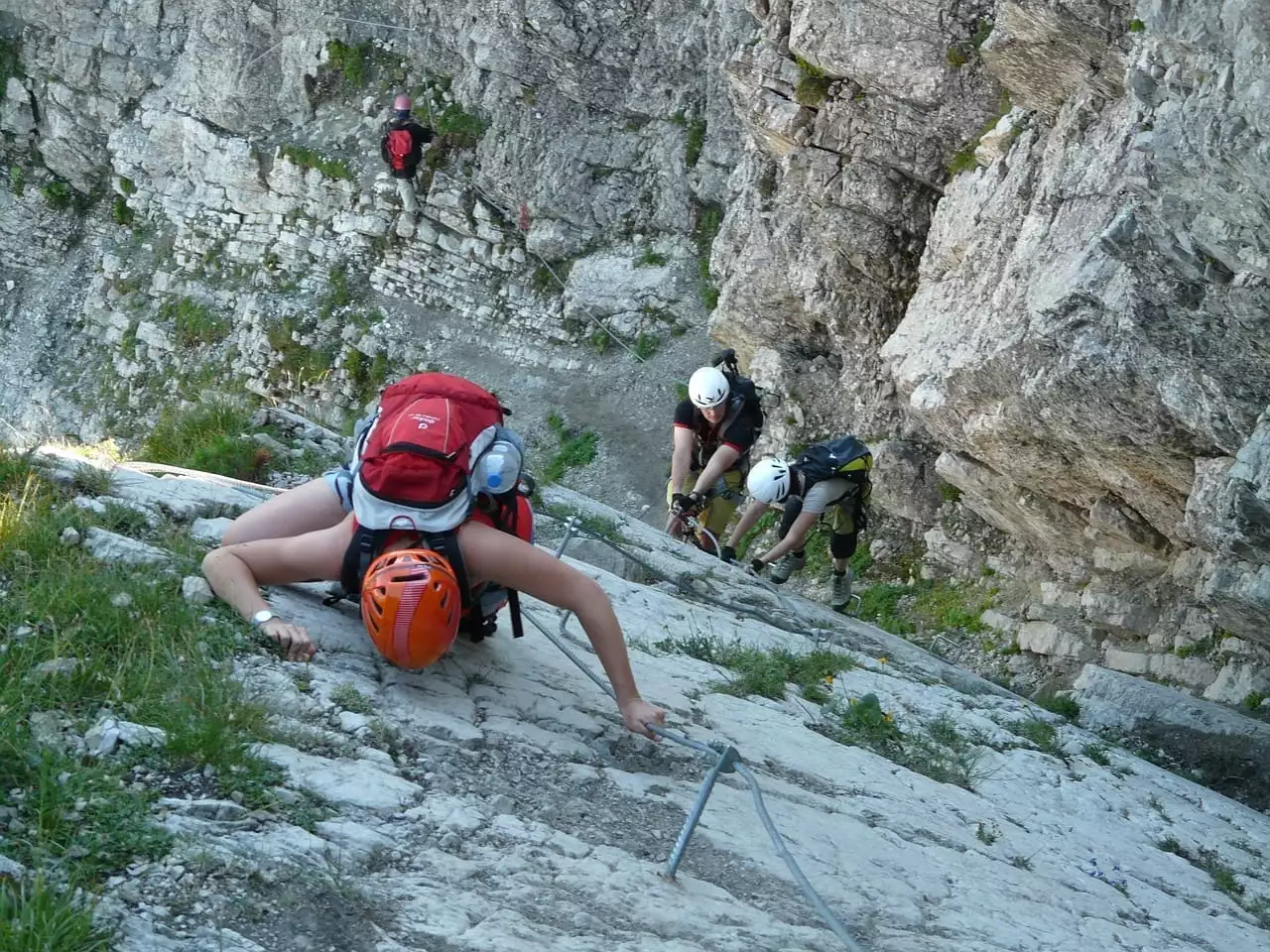 Woman climbs up a vertical rockface - photo: Pixabay