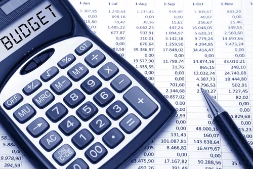 'Budget' in text on a calculator screen, on a spreadsheet print-out with pen
