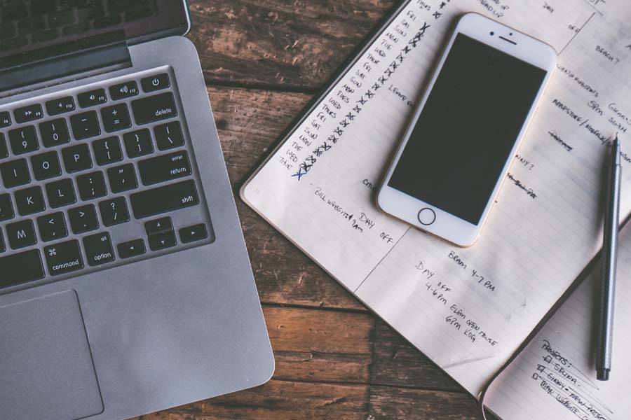 Laptop, phone and notebook on a desk