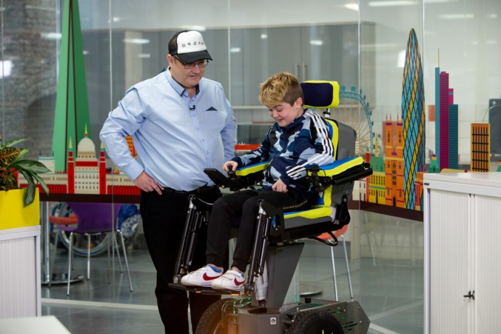 Eli tests out the new wheelchair with Wheels of Change project manager Frank Robertson. Photo: Whizz Kids