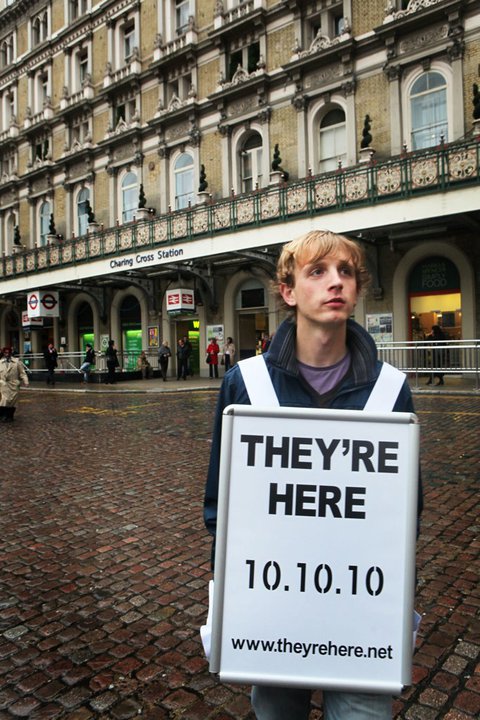 Man wearing a OneKind 'They're Here' sandwich board outside Charing Cross Station, London