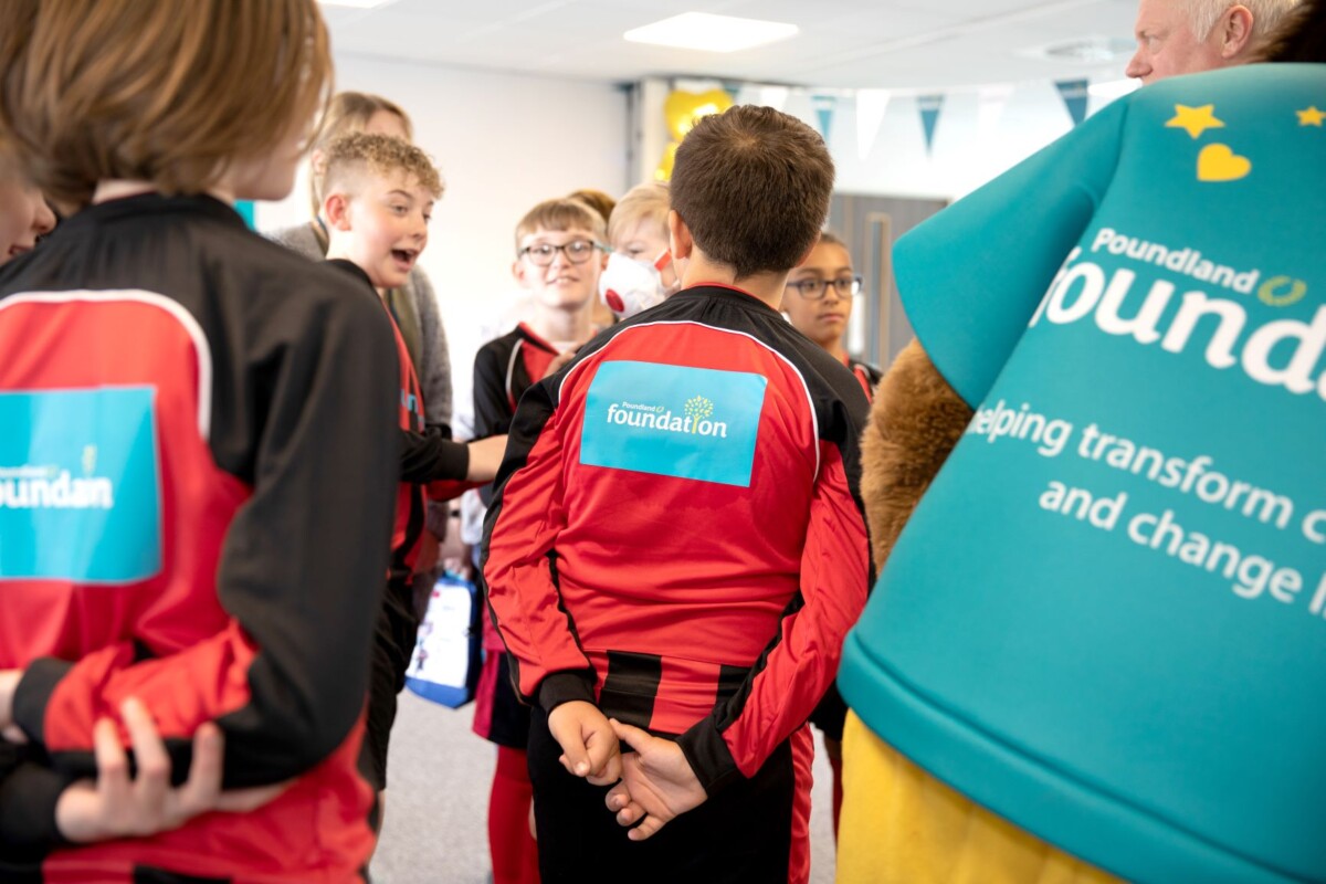 People stand with their backs to the camera, wearing tops that say Poundland