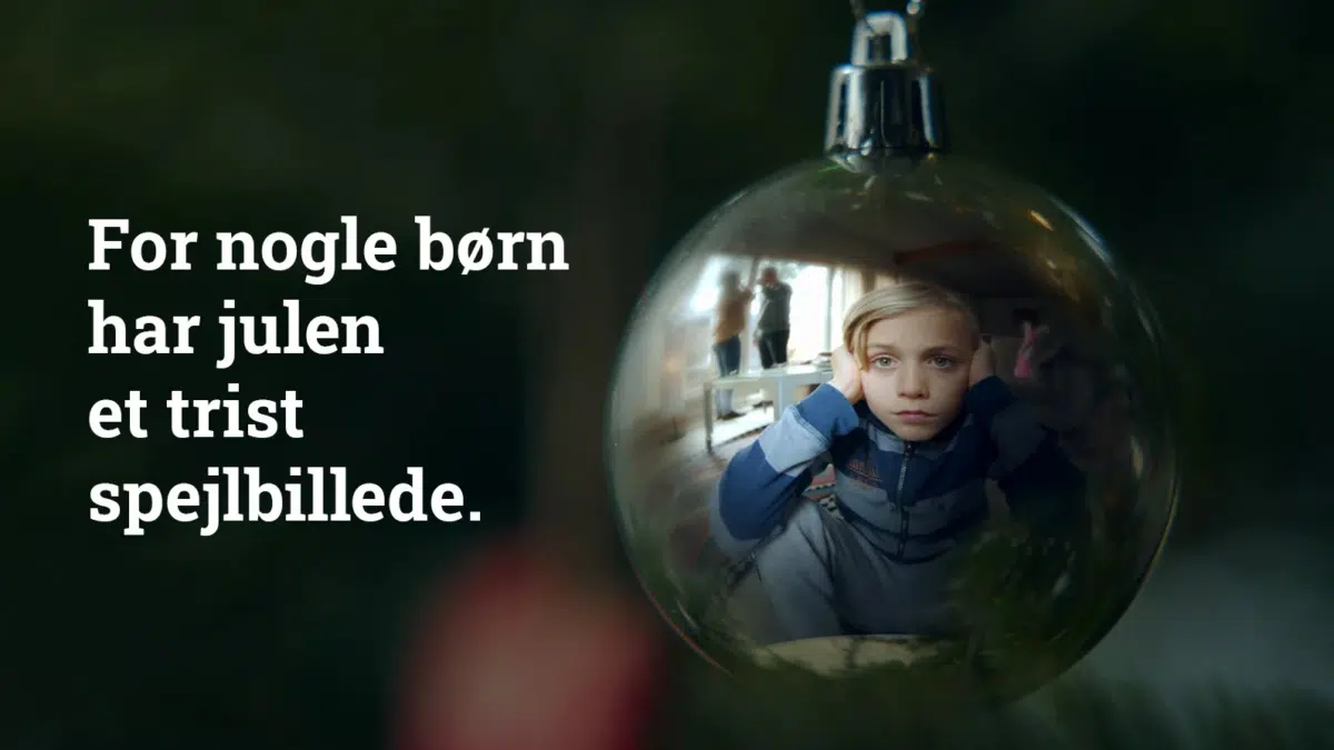 For nogle børn har julen et trist spejlbillede.Image of a shiny Christmas bauble with a childre's face reflected in it.