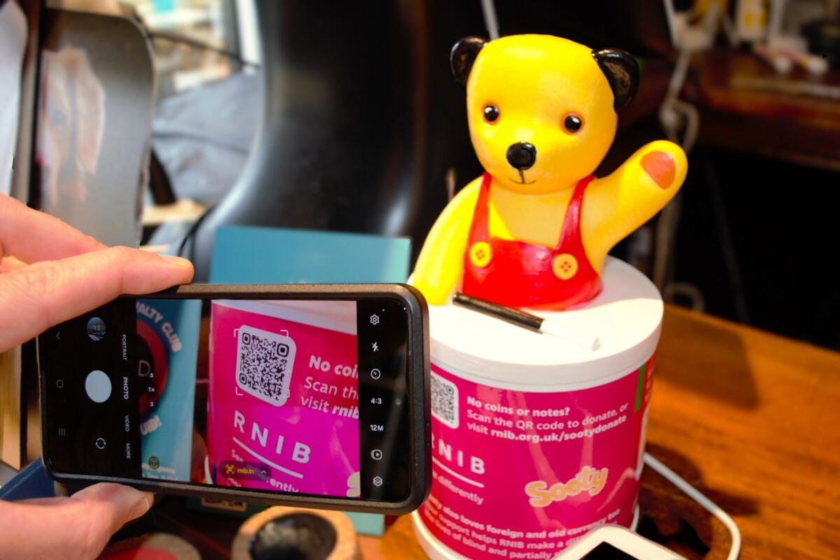 Scanning a QR code on a Sooty Collection Box for the RNIB