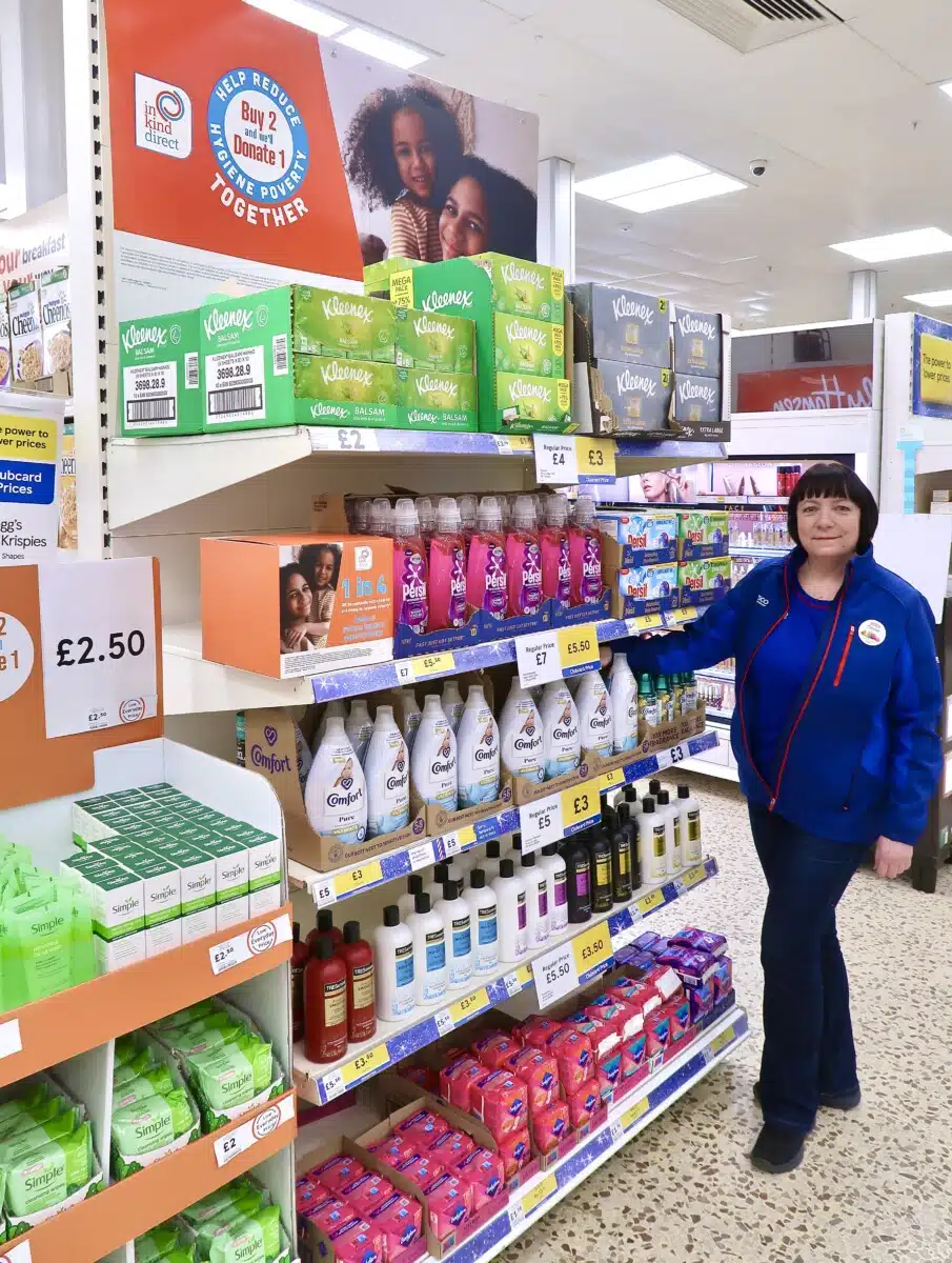 A Tesco worker stands next to an in-store promotion of the In Kind Direct and Tesco campaign for hygiene products.