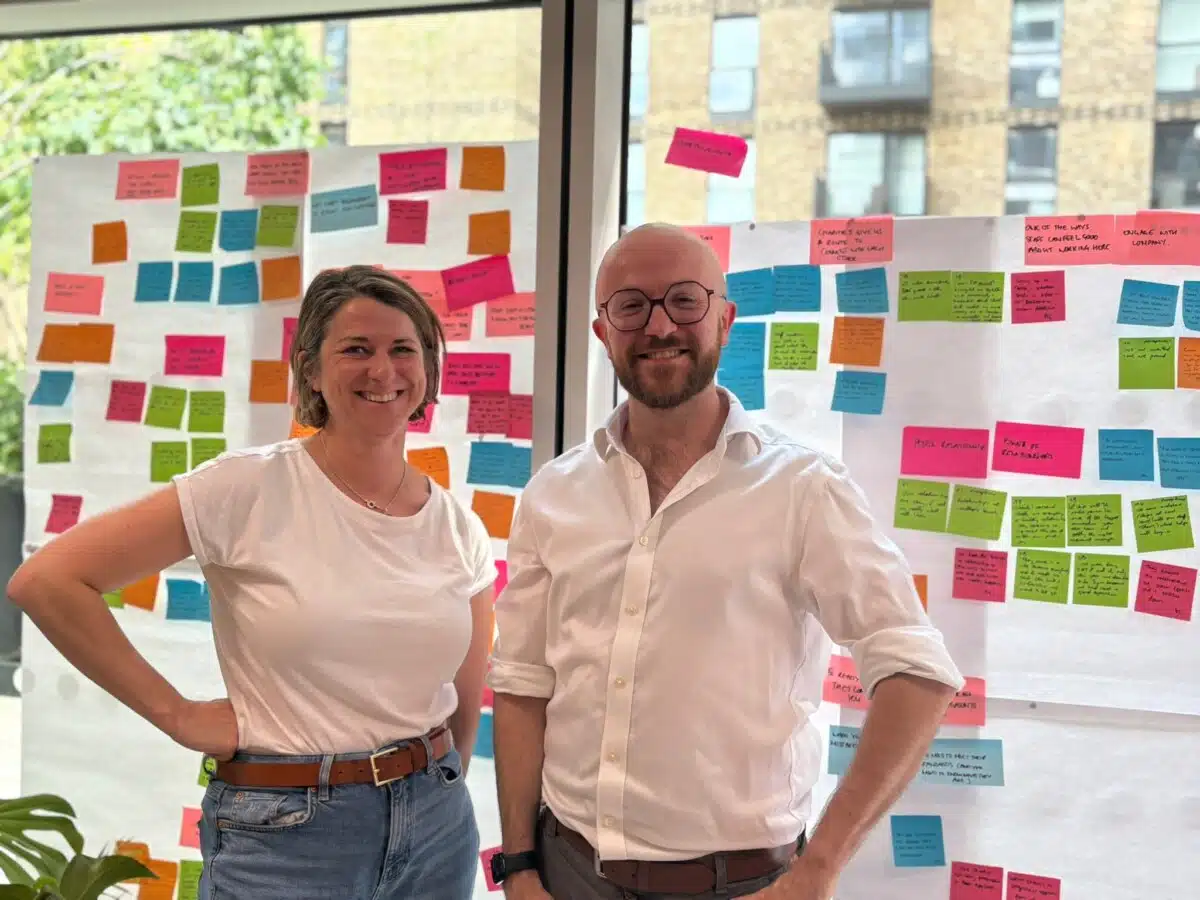Lesley Pinder and Andy King, in front of two windows covered in coloured post-it-like sticky notes with writing on.