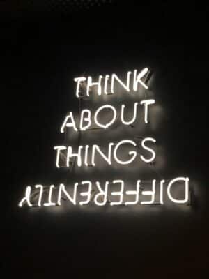 Neon sign on black background - "think about things differently".