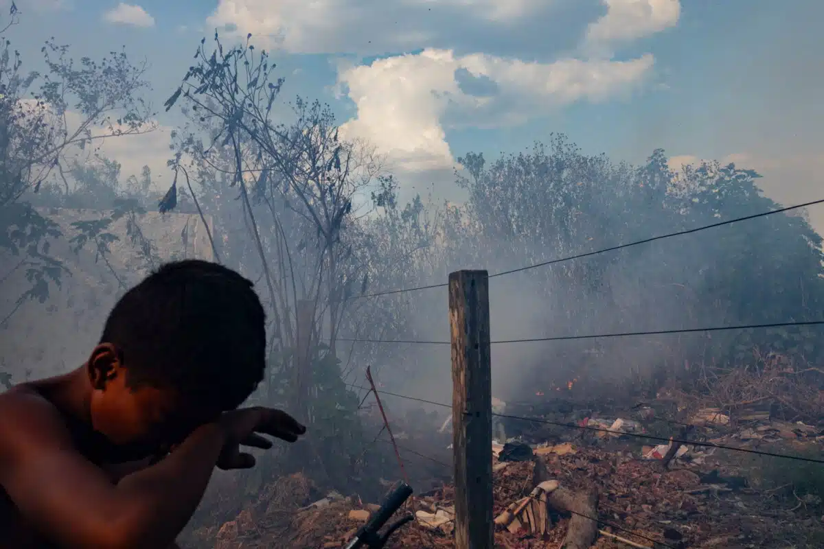Children hide from the smoke in a rural area in the city of Senador Guiommard in the state of Acre. During the months of August, September, and October, the Amazon region historically suffers from urban and forest fires, filling the skies with smoke. Acre State, Brazil. August 11 2025.