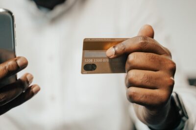 Close-up of a debit card being held next to a mobile phone, a payment about to be made.
